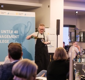 Wein wird am Tisch eingeschenkt, im Hintergrund die Top-40-unter-40-Bühnenwand